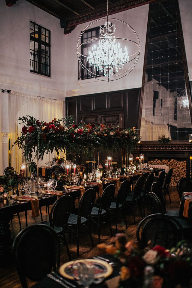 the dining room is set up for a formal function with chandeliers and floral centerpieces