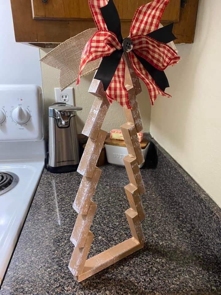 a wooden christmas tree with a bow on it's top in a kitchen area