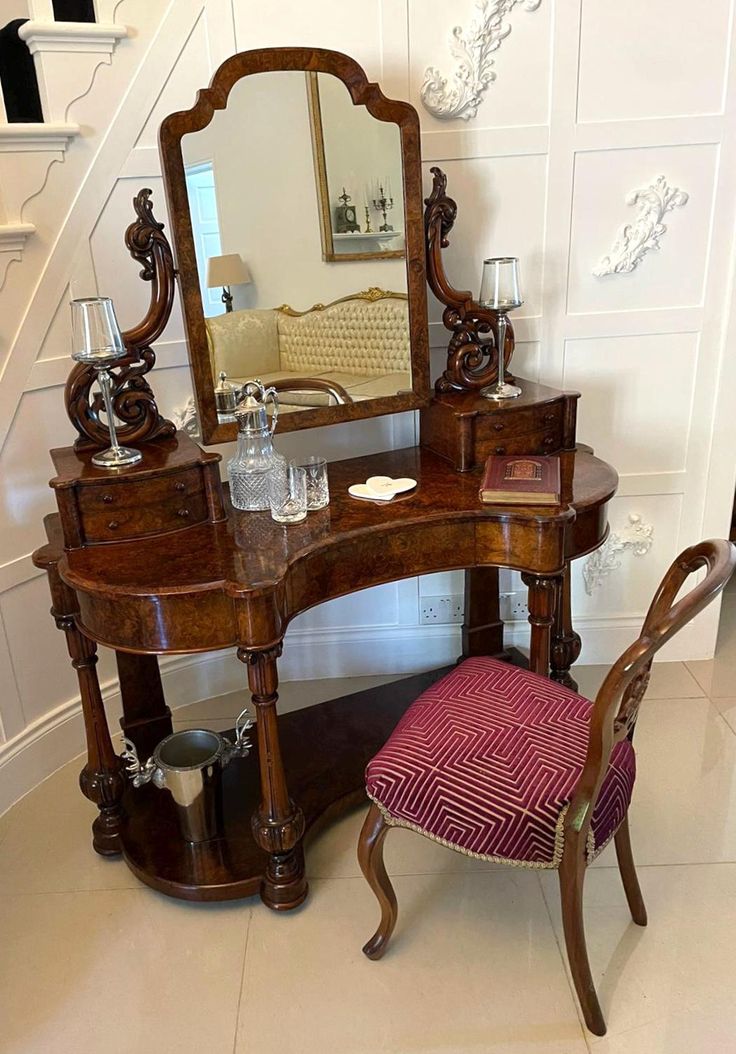 a dressing table with mirror, stool and wine glass on it in front of stairs