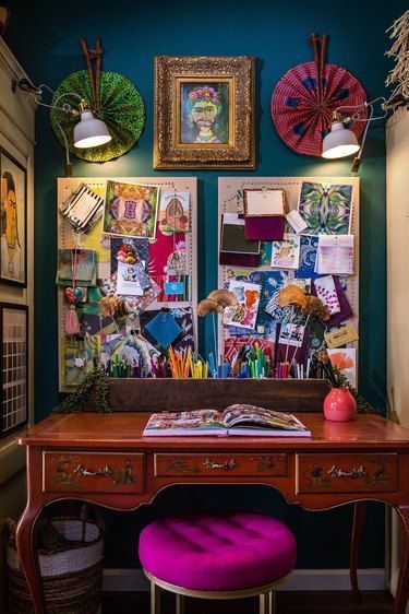 a desk and chair in a room with many pictures on the wall above it,