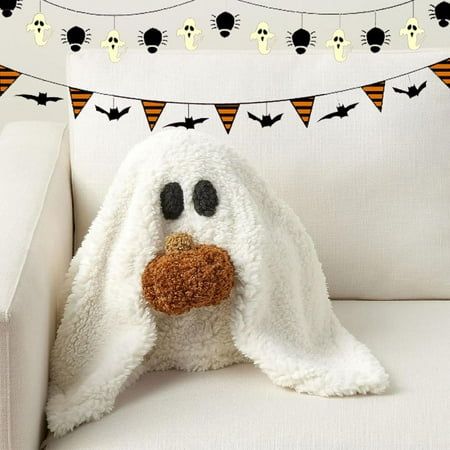 a stuffed animal is sitting on a white couch with halloween decorations around it and bunting