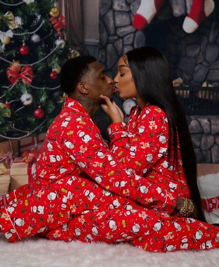 a man and woman are kissing in front of a christmas tree