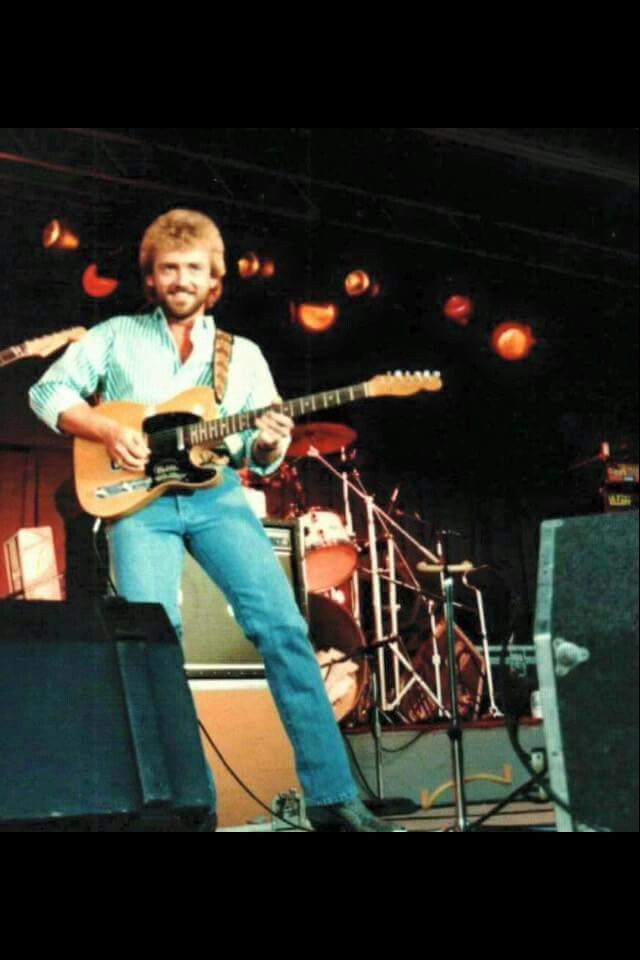 a man standing on top of a stage holding a guitar