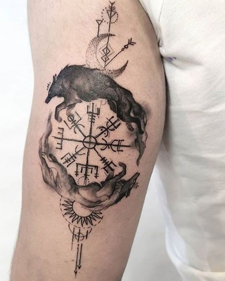 a man with a tattoo on his arm holding a compass and dolphin in the middle