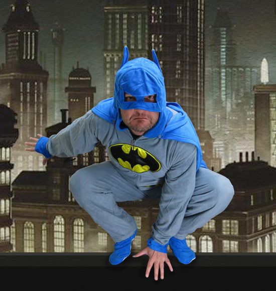 a man dressed as batman poses for a photo in front of a cityscape