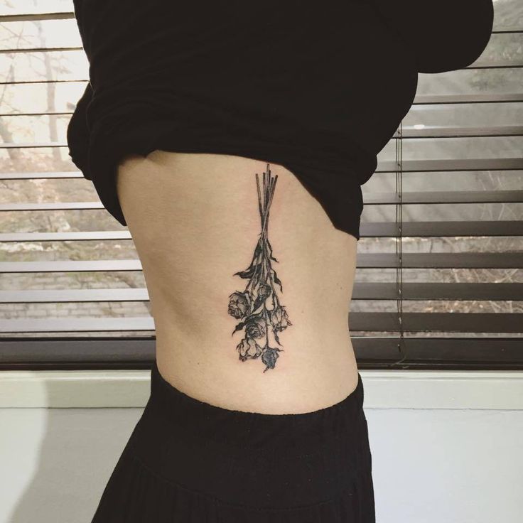 a woman's lower back tattoo with flowers on her ribs and the bottom part of her stomach