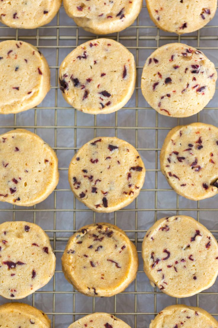 several cookies cooling on a wire rack with cranberries in the middle and one cookie missing