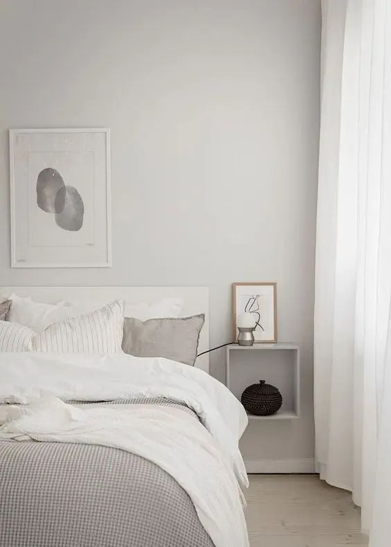 a bedroom with white walls and wood flooring is pictured in this image, the bed has