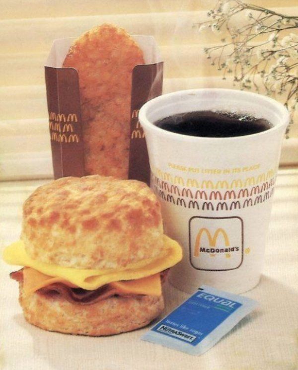 a cup of coffee next to a biscuit sandwich and a mcdonald's card