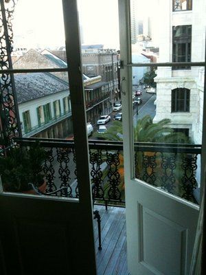 an open door leading to a balcony with cars parked on the street