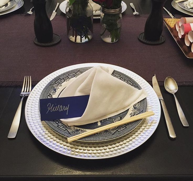 a place setting with silverware and napkins on a black tablecloth covered table