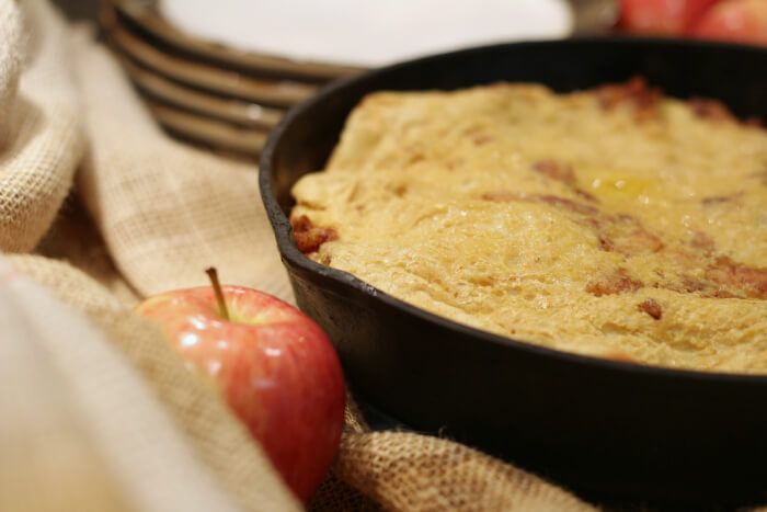 an apple pie in a cast iron skillet on a table with plates and napkins