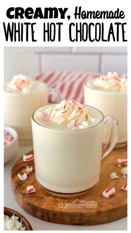 two cups filled with white hot chocolate on top of a wooden cutting board next to some candy canes