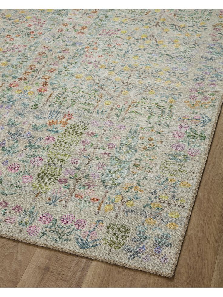 an area rug with various colored flowers and leaves on the floor in front of a wooden floor