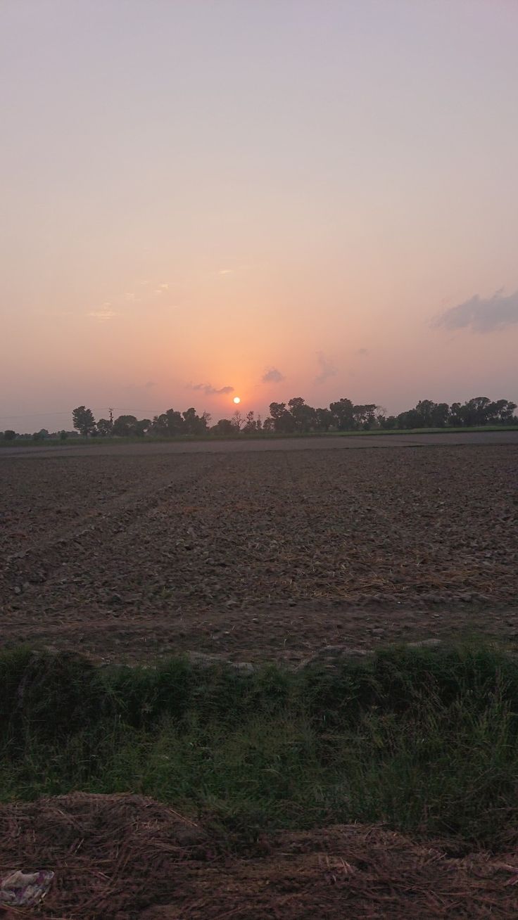 the sun is setting over an empty field