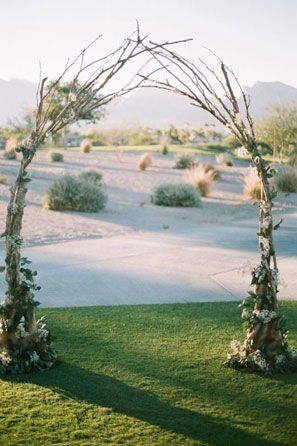 an outdoor wedding setup with white flowers and greenery on the grass in front of mountains