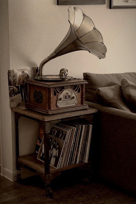 an old fashioned record player sitting on top of a table next to a couch in a living room