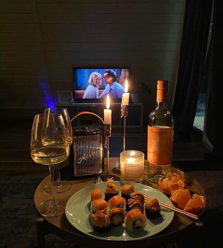 a table topped with food and wine next to a tv