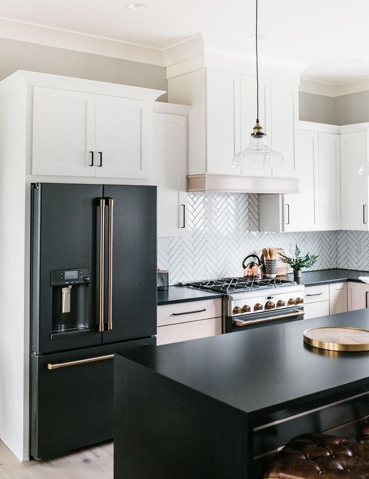 a kitchen with white cabinets and black counter tops, an island in the middle is surrounded by stools