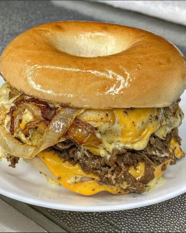 a sandwich with meat, cheese and onions on a white plate