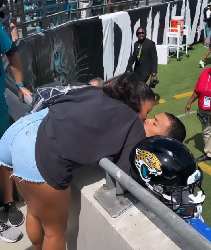 a woman kissing a football player on the sidelines