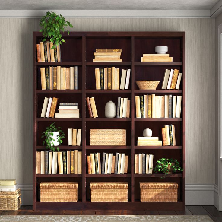 a bookshelf filled with lots of books next to a plant in a room