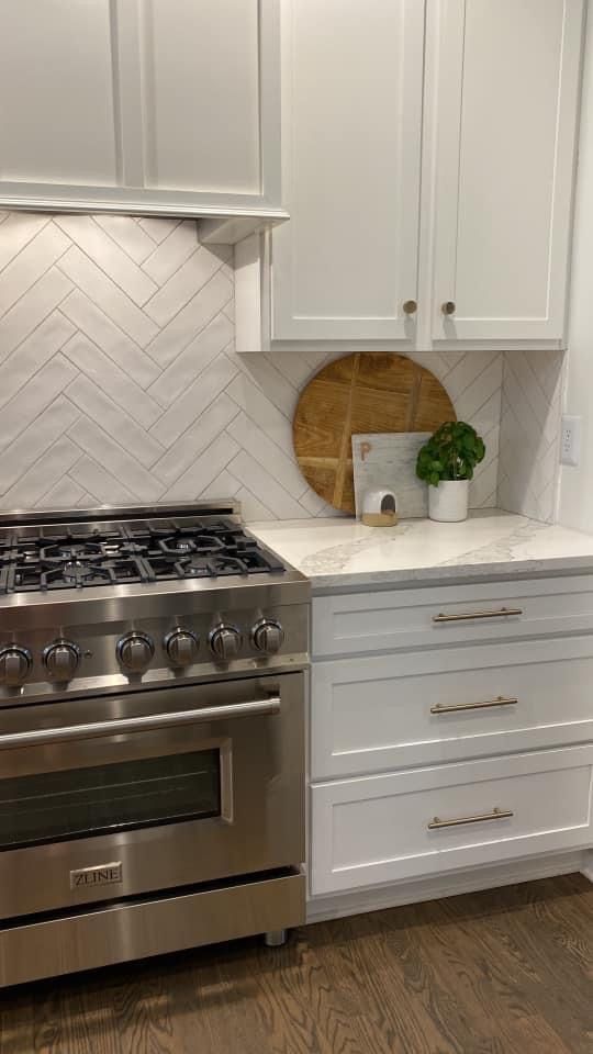 a stove top oven sitting inside of a kitchen next to white cabinets and wooden floors