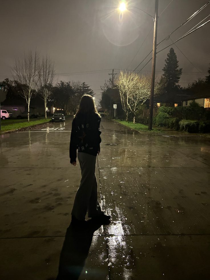 a woman walking in the rain at night