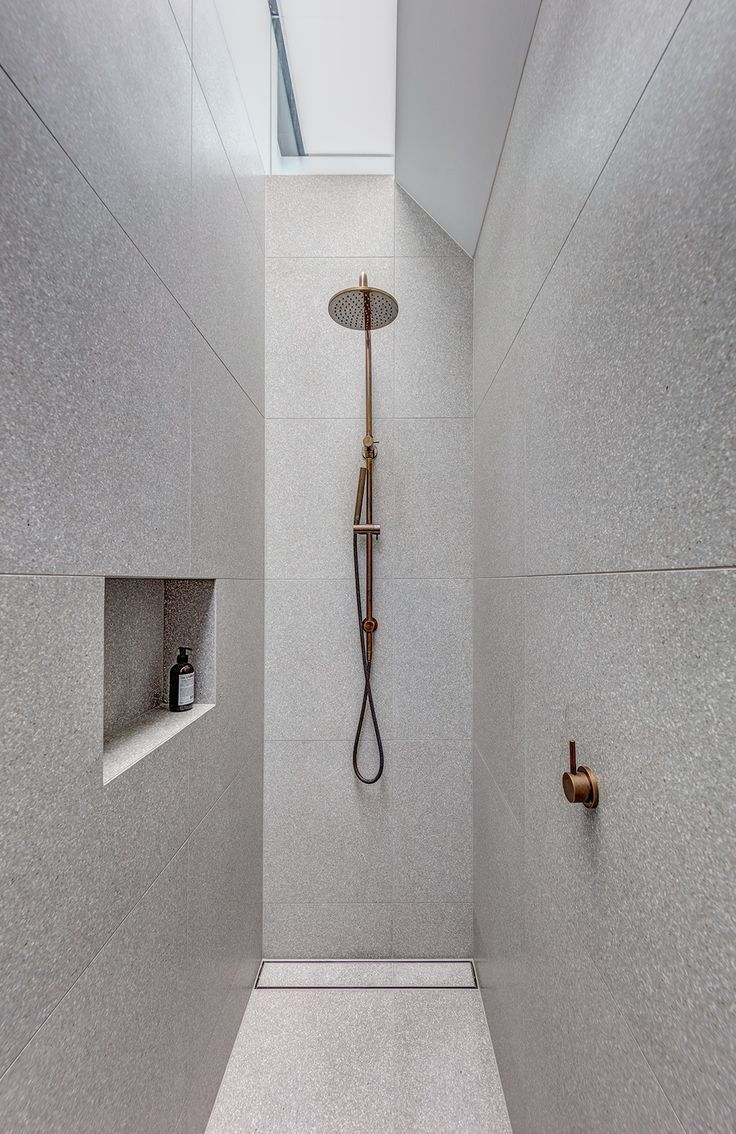 a walk in shower sitting under a skylight next to a shelf filled with bottles