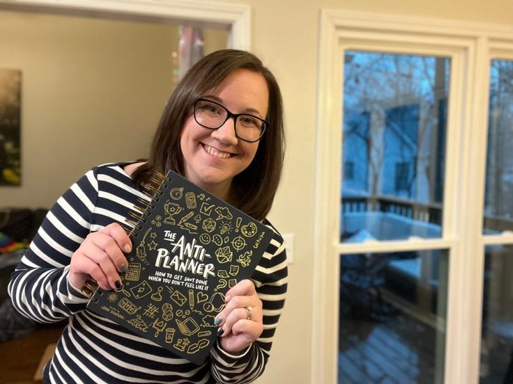 a woman holding up a book in front of her face and smiling at the camera