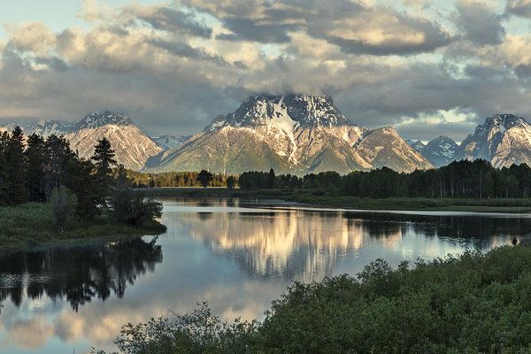 the mountains are reflected in the calm water