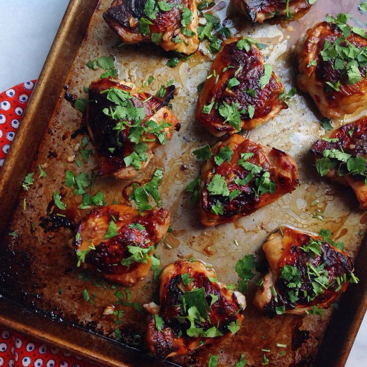 chicken with cilantro sauce and parsley on a baking sheet, ready to be cooked