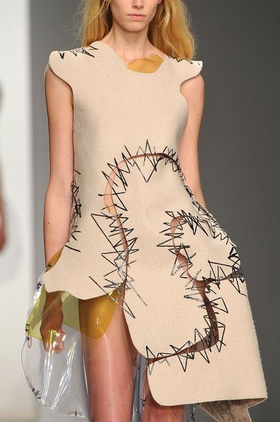 a model walks down the runway in a short dress with holes on it's sides