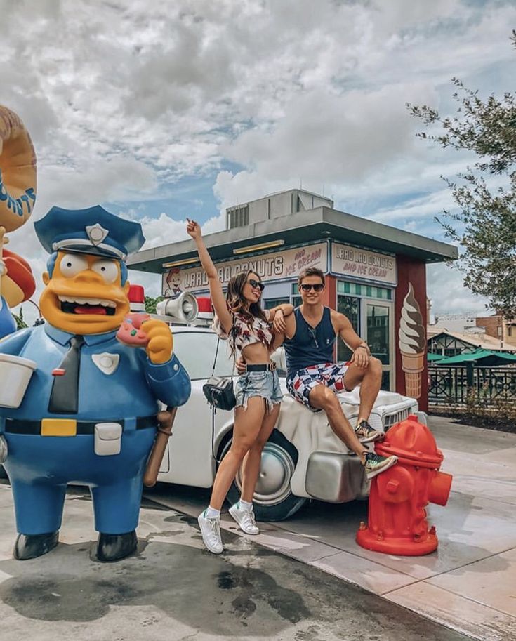 two people sitting on the back of a car in front of a fire hydrant