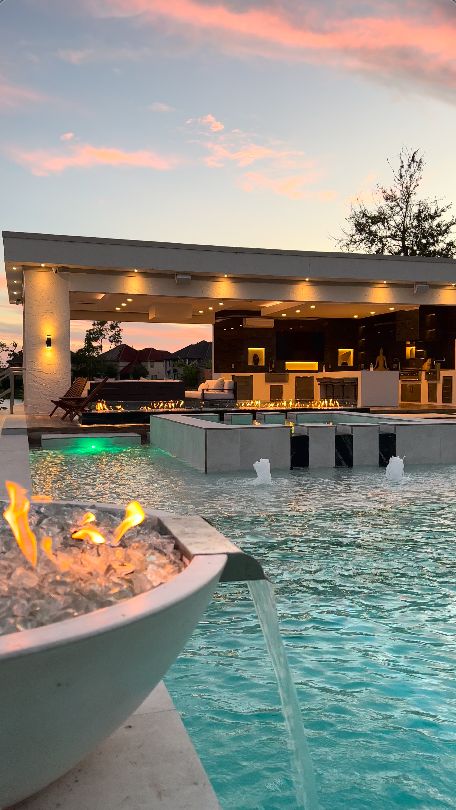 an outdoor swimming pool with fire pit at sunset