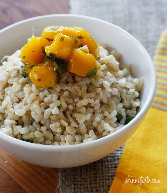 a white bowl filled with rice and vegetables on top of a wooden cutting board next to a yellow towel