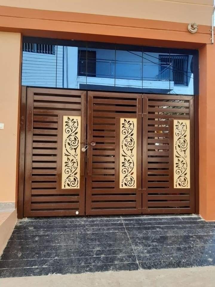 two wooden doors with decorative designs on them in front of a building that has an orange wall