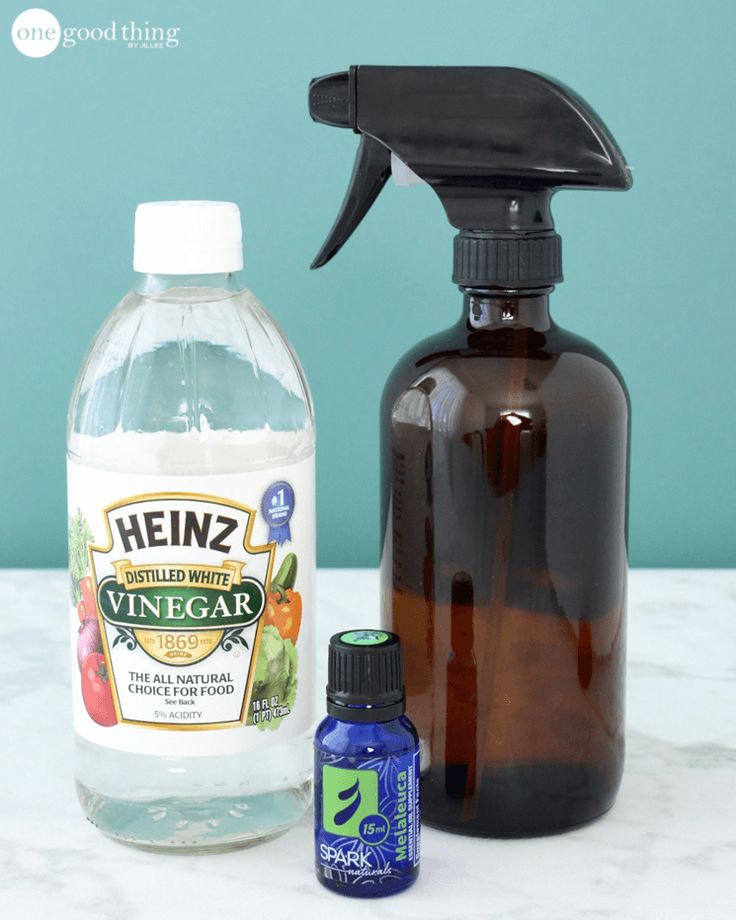 a bottle of vinegar next to an empty glass bottle with cleaner and deodorant on it