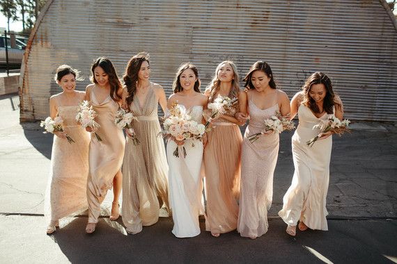 a group of women standing next to each other in long dresses and holding bouquets