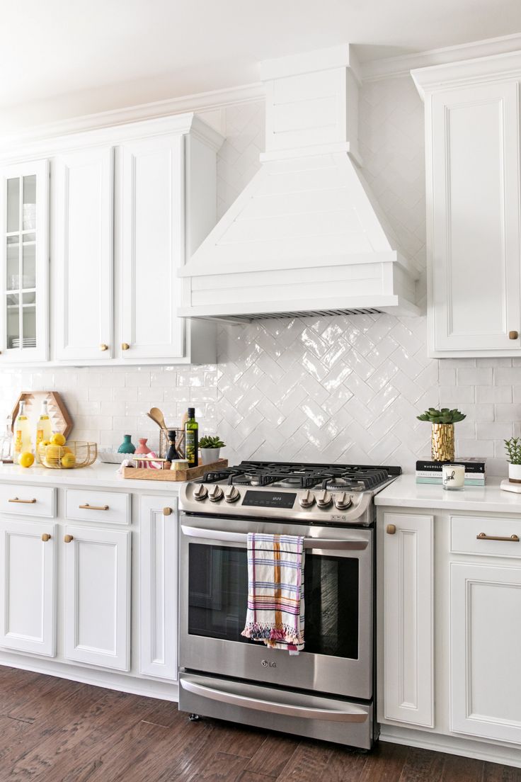 a stove top oven sitting inside of a kitchen next to white cabinets and wooden floors