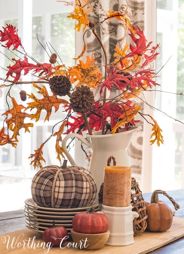 a white vase filled with lots of autumn decorations