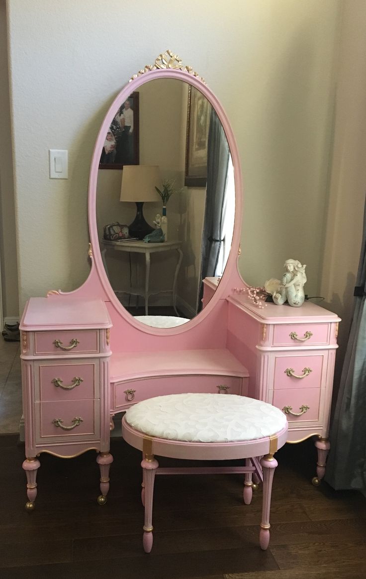 a pink vanity with mirror and stool in a room