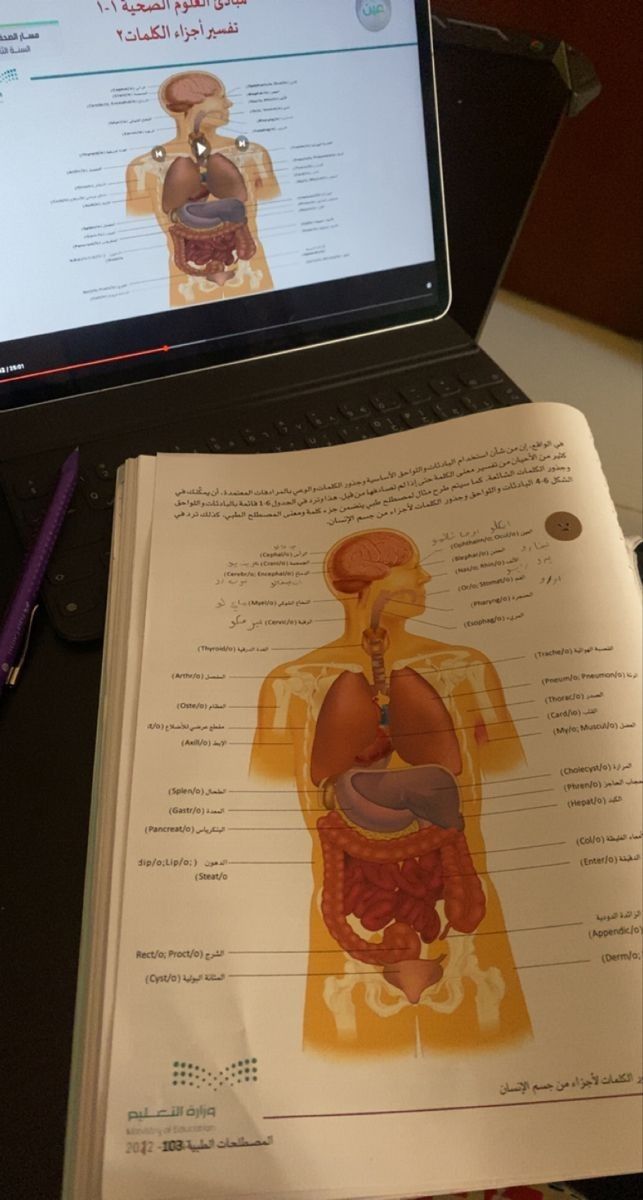 a laptop computer sitting on top of a desk next to an open book and pen