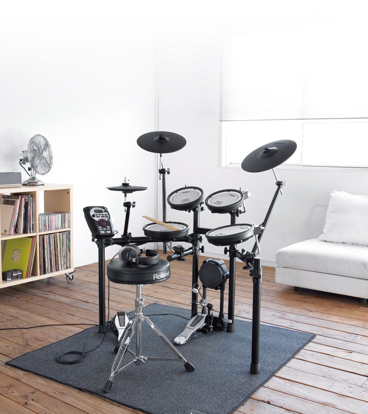 a drum set is sitting on a rug in the middle of a room with bookshelves