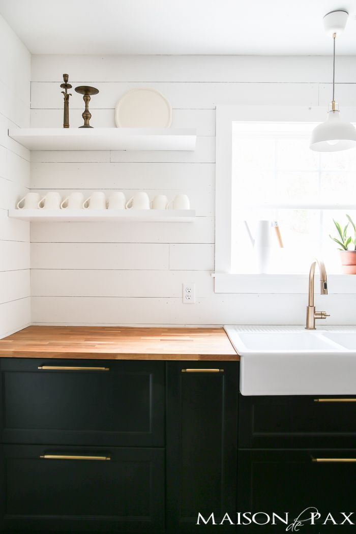 a kitchen with black cabinets and white shiping on the backsplash is seen in this image