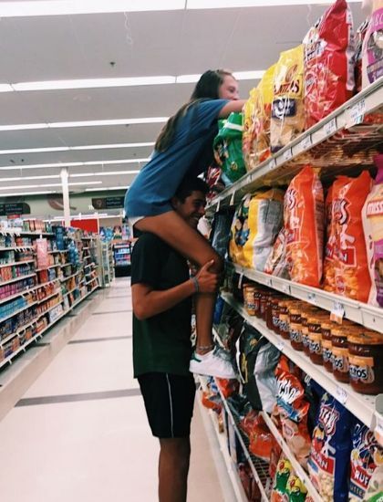 a man is standing on top of a woman's head in the aisle of a grocery store