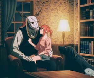 a man and woman sitting on a couch in front of a bookshelf