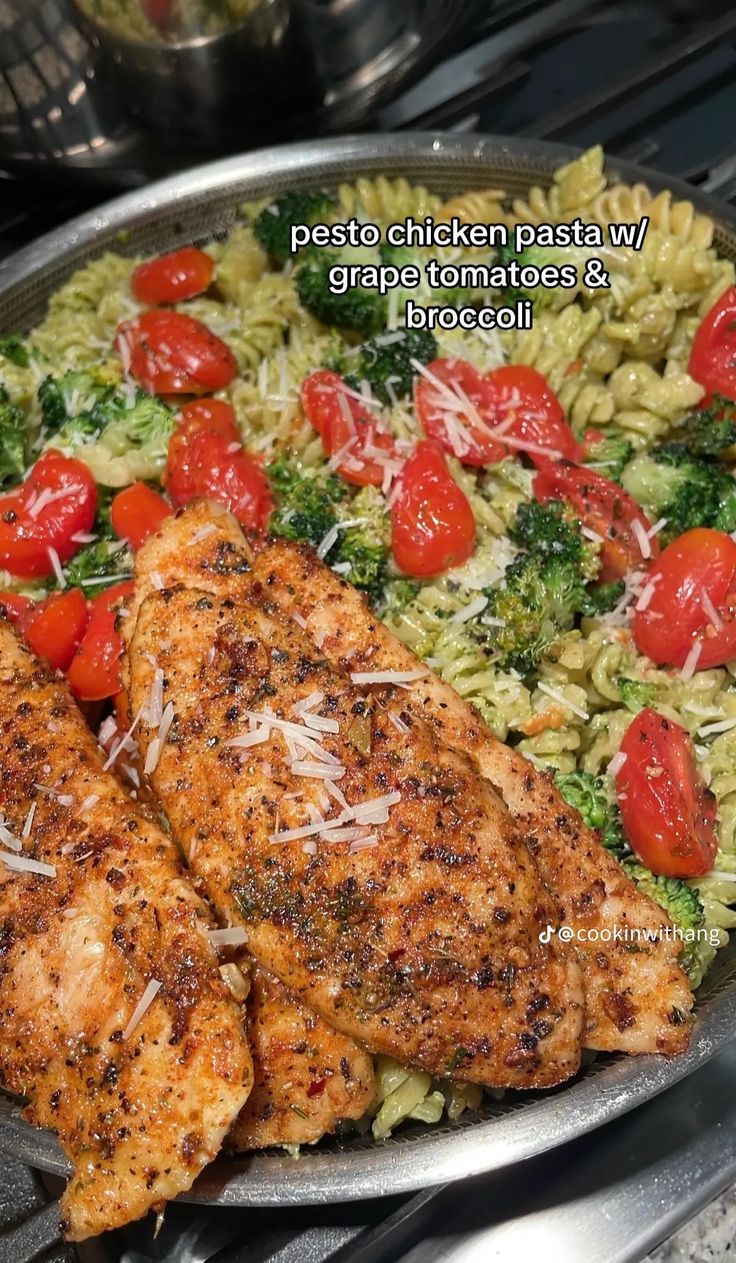 two pieces of chicken with tomatoes and broccoli in a pan