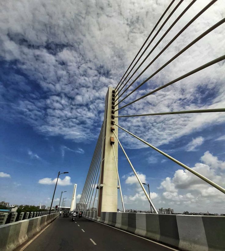 the bridge is very tall and has many cables on it's sides, as well as cars driving down the road