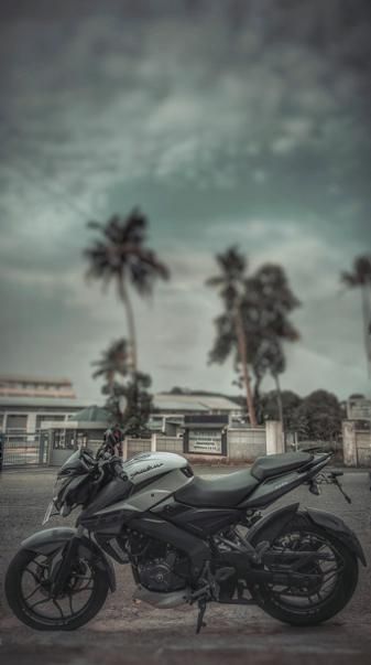 a motorcycle is parked on the street in front of some palm trees and a building